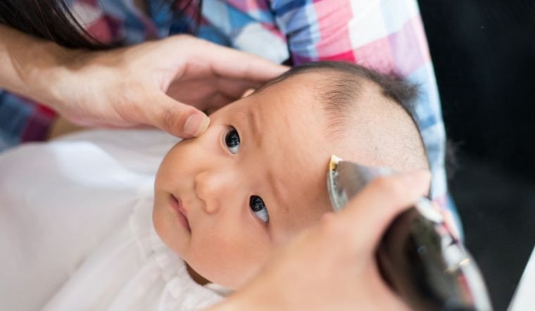 Người lớn cẩn thận cắt tóc cho em bé, thể hiện sự quan tâm đến thời điểm cắt tóc bé ngày nào tốt theo phong tục.