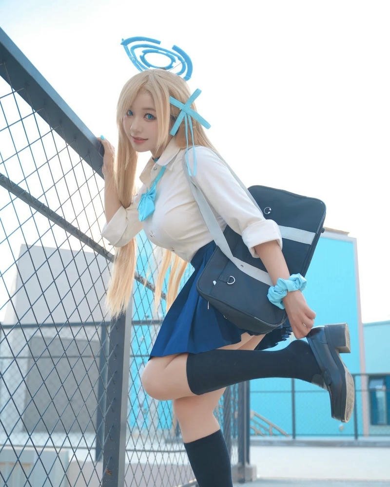 Cosplay học sinh tóc vàng váy xanh đứng ngoài trời nắng