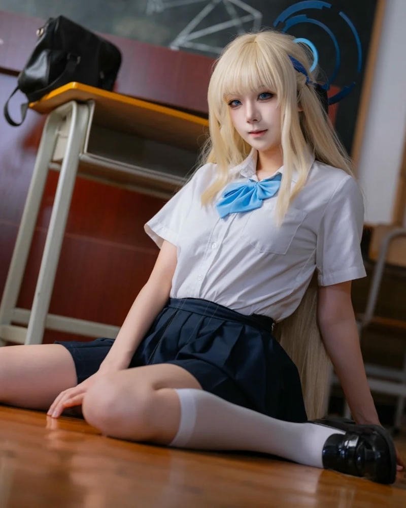 Cosplay học sinh tóc vàng váy xanh ngồi trên bậc thang
