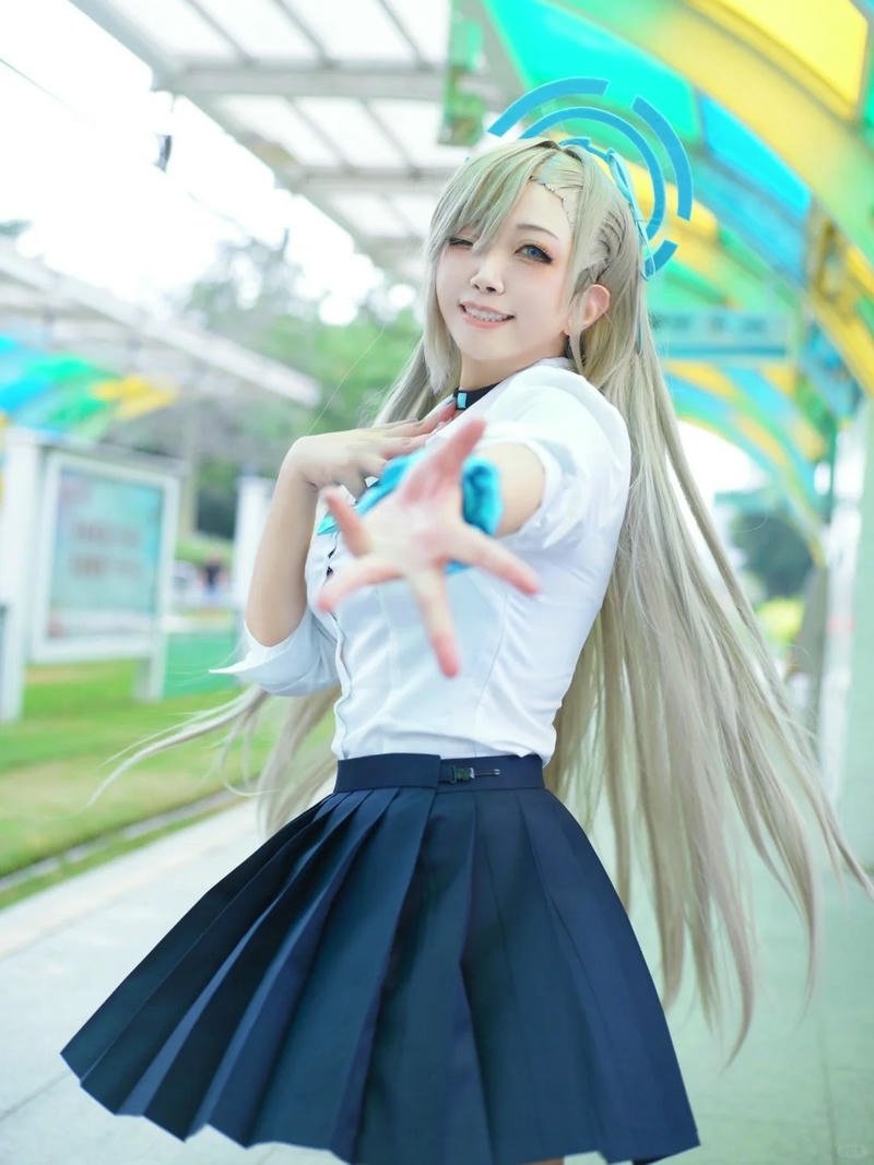 Cosplay học sinh tóc vàng váy xanh tạo dáng trái tim