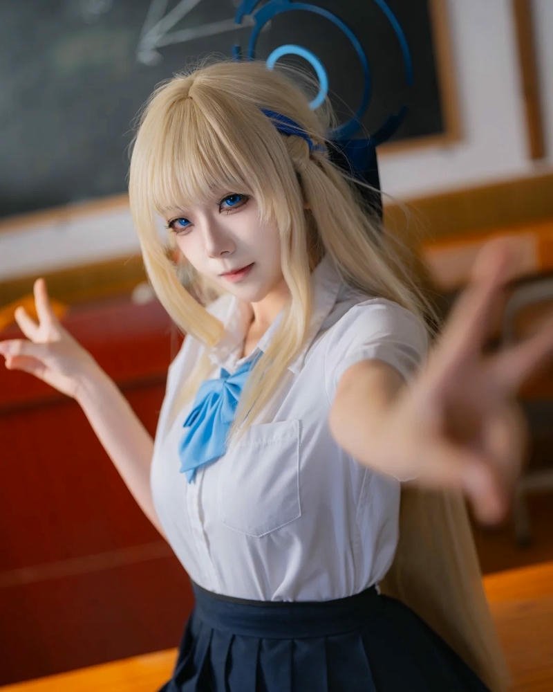 Cosplay học sinh tóc vàng váy xanh vươn tay về phía trước