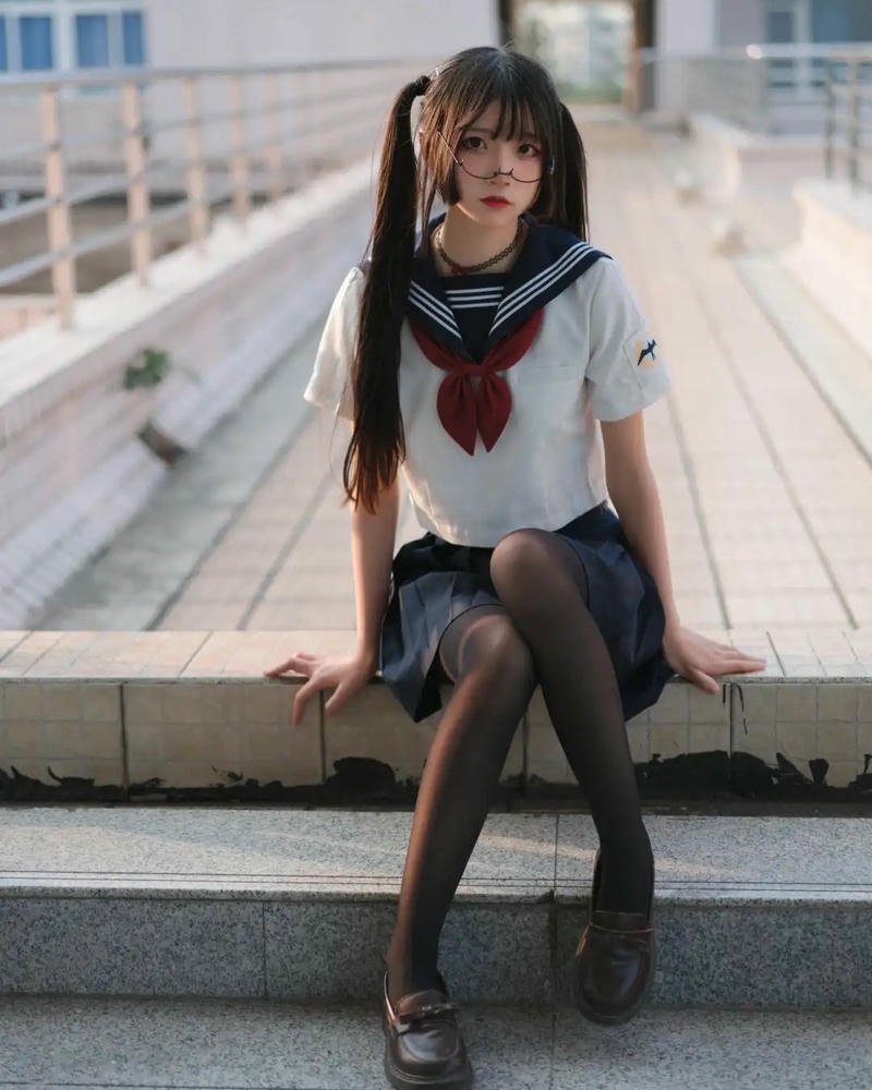 Nữ sinh cosplay đồng phục thủy thủ ngồi trên ghế nhìn xuống