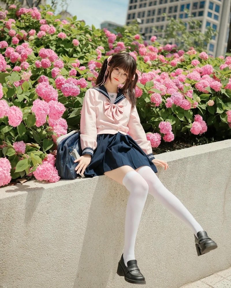 Nữ sinh dễ thương ngồi trên tường rào hoa