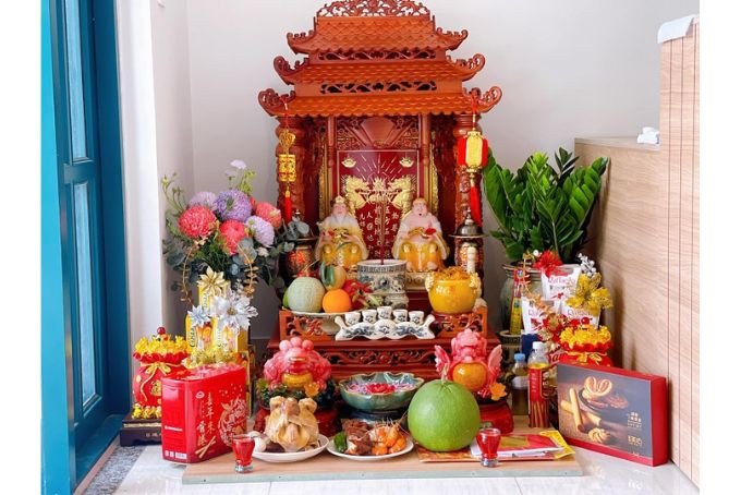 Bàn thờ Thần Tài bày lễ vật và nến sáng trong ngày mùng 1 hoặc rằm