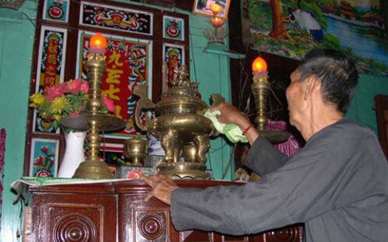 Cận cảnh việc lau dọn một pho tượng Phật trên ban thờ, nhấn mạnh quy trình vệ sinh từ trên cao xuống dưới để giữ sự trang nghiêm.