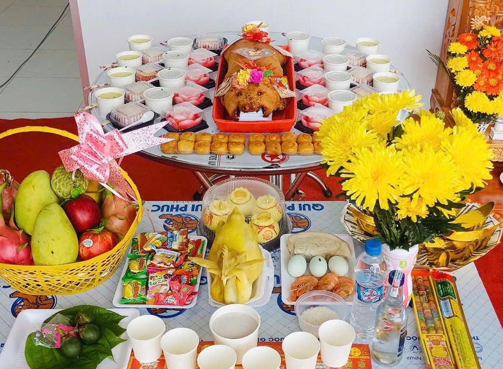 Một mâm cúng khai trương đầy đủ với các loại trái cây tươi ngon, xôi, chè và vật phẩm tâm linh khác, thể hiện sự cầu thị và mong muốn thịnh vượng