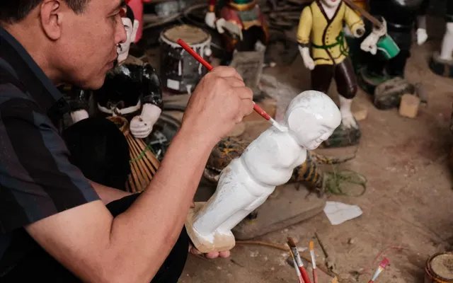 Nghệ nhân đang tỉ mỉ chạm khắc chi tiết cho một con rối nước từ một khúc gỗ sung