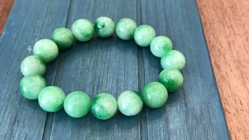 Ngọc cẩm thạch xanh lá cây hình oval đặt trên mặt bàn gỗ