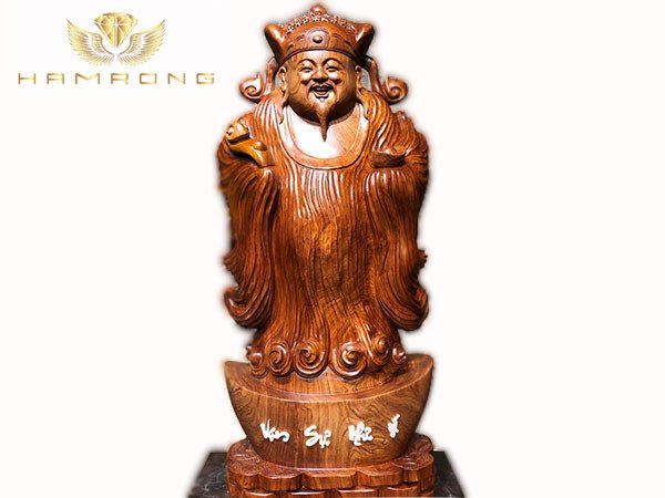 Tượng gỗ Thần Tài với nụ cười hiền hậu, tay cầm thỏi vàng, đặt trên bàn thờ