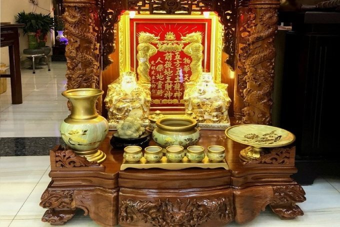 Tượng Ông Thần Tài và Ông Địa trên bàn thờ với lễ vật cúng