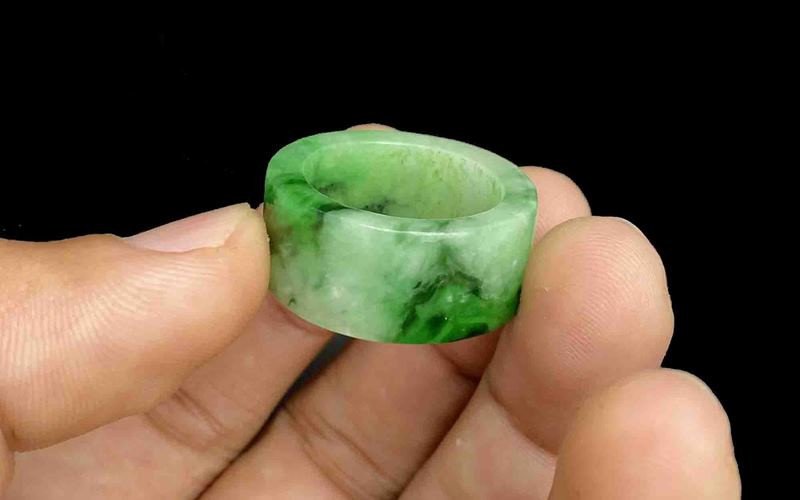 Vòng tay ngọc cẩm thạch xanh và các viên ngọc rời trên bàn gỗ